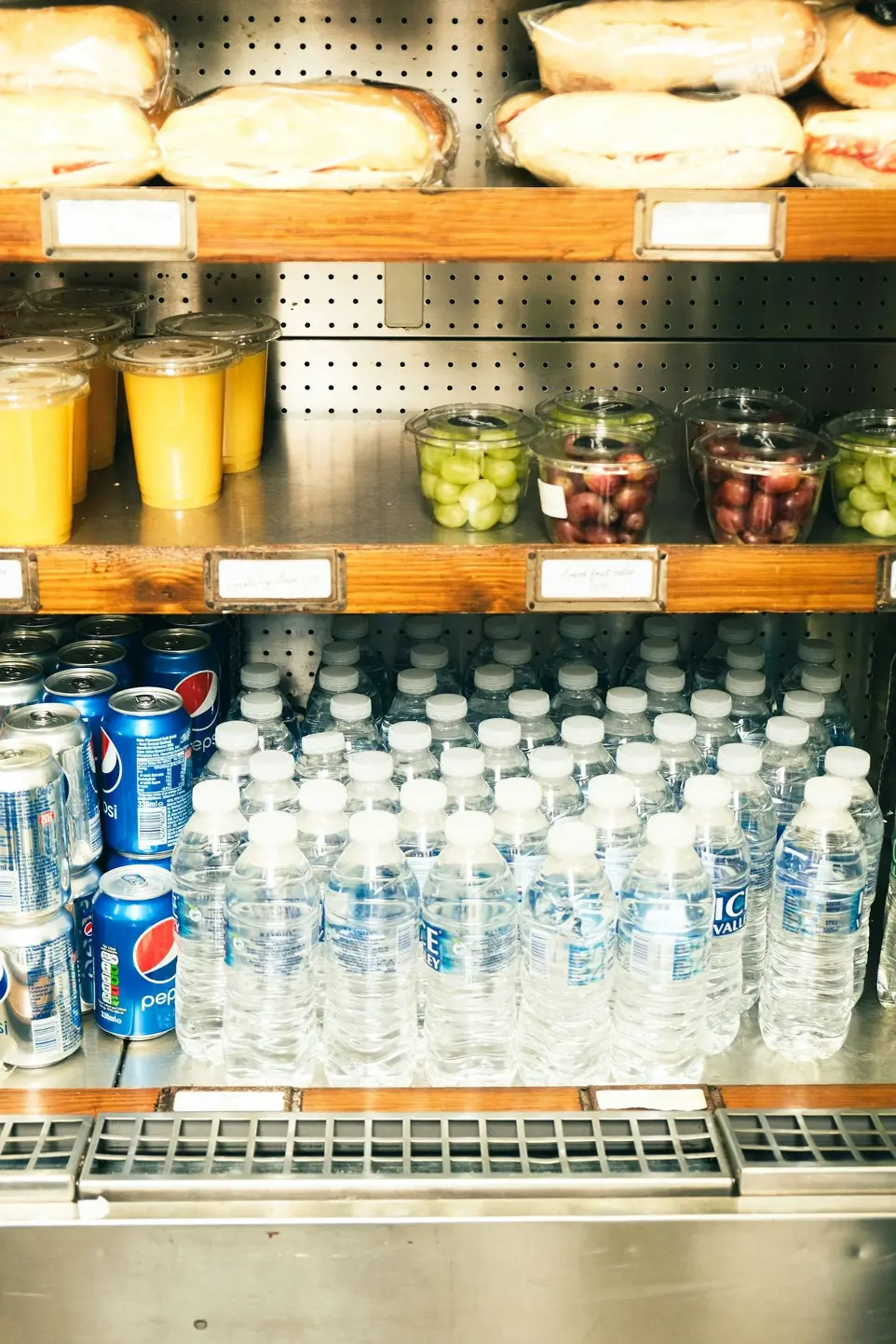 A store shelf filled with bottled water and fruit